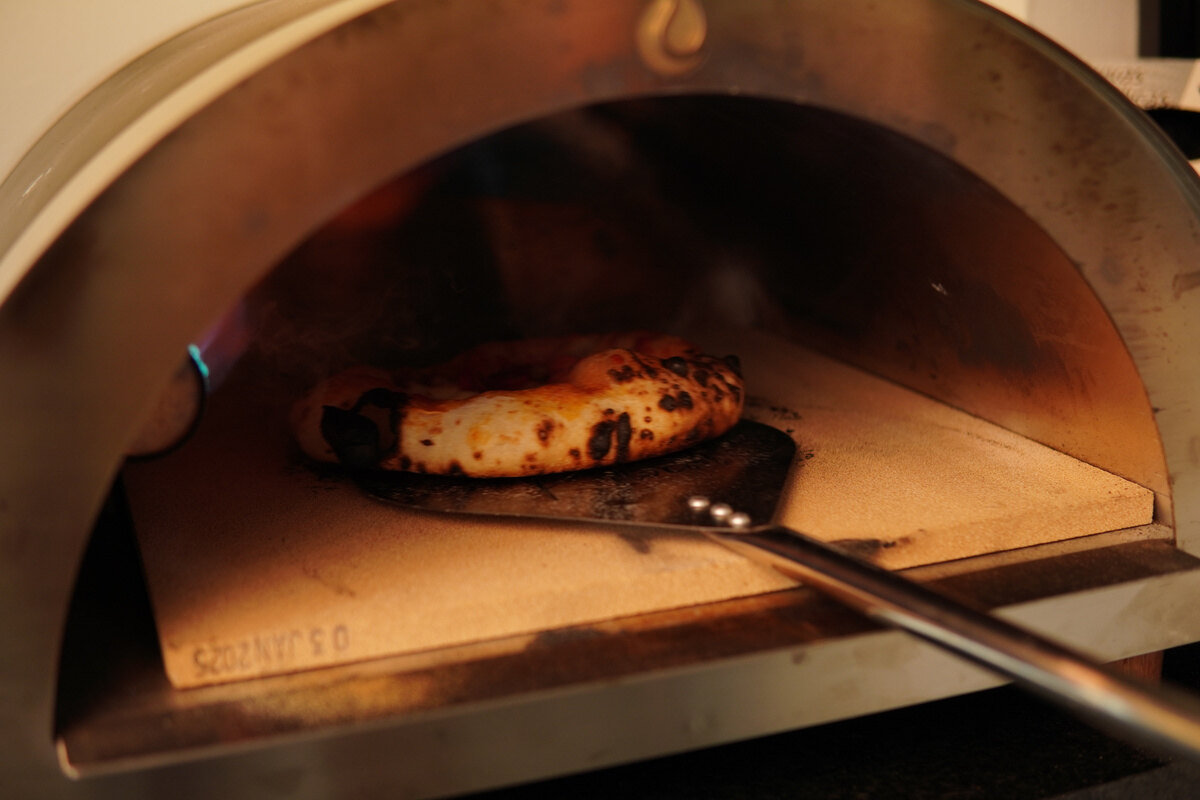 Pizza artesanal sendo assada no forno durante um evento da Trigô