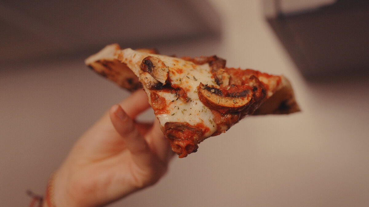 Convidado segurando uma fatia de pizza artesanal